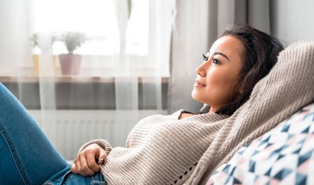 Asian girl at home deep in thoughts thinking and planningの写真素材
