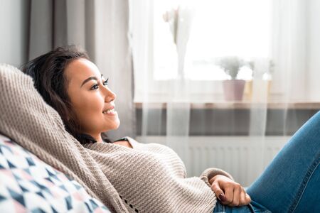 Relaxed asian girl lying on sofa at home in calm leisure timeの写真素材