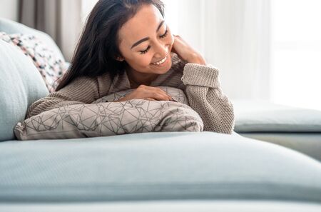 Relaxed asian girl lying on sofa at home in calm leisure timeの写真素材