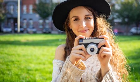 Lifestyle portrait of stylish girl with retro camera during walk in city streetの写真素材
