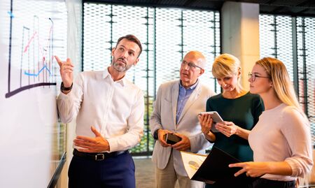 Business people in front of white board gives presentation report at conference roomの写真素材