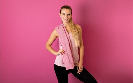Fit woman after workout with towel on her shoulders on pink backgroundの写真素材