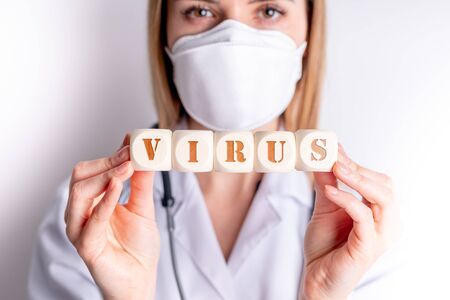 Virus concept wooden blocks in hand of female doctorの写真素材