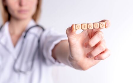 Virus concept wooden blocks in hand of female doctorの写真素材