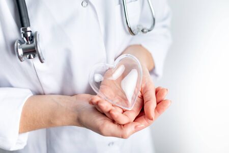 Female cardiologist doctor holding heart symbol on handsの写真素材
