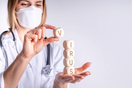 Virus concept wooden blocks in hand of female doctorの写真素材