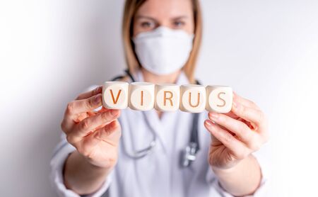 Virus concept wooden blocks in hand of female doctorの写真素材