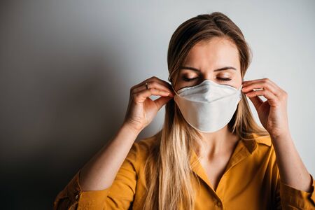 Virus mask woman puts on face protection in prevention for coronavirusの写真素材