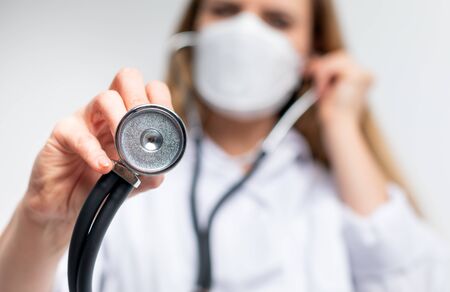 Female doctor with a stethoscope and virus protective mask medical care conceptの写真素材