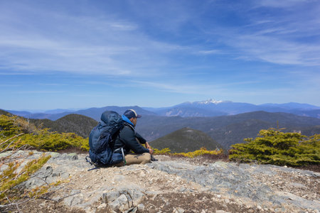 Hiker sitting on top of a mountain and looking at the view