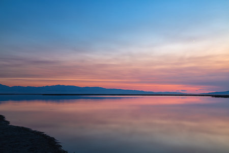 Sunset on the lake with reflection of the mountains in the waterの写真素材