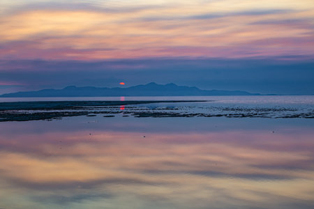 Sunset at the beach in the evening with reflection in the waterの写真素材
