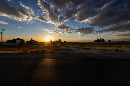 Sunset in a rural area with a road leading out to the horizonの写真素材