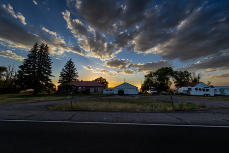 Sunset in a small town with houses, trees and clouds in the skyの写真素材