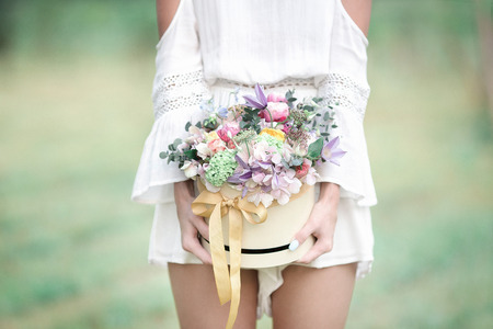 Young girl with flowers in summer hat posing on fieldの写真素材