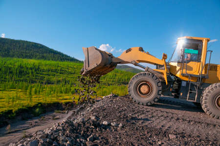 Front-end loader in a mountainous forest area on a summer sunny day.の写真素材