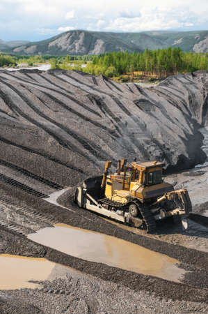 Bulldozers in mountainous wooded areas, layer by layer, remove mountain soil from the surface and...