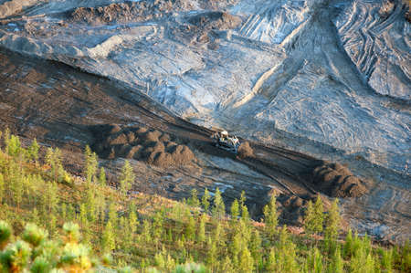 Bulldozer clears an area in a mountainous woodland with an industrial bucket. View from the mountain to the construction site.の写真素材