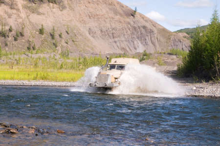 Lorry - a fuel tanker overcomes a water obstacle in a mountainous wooded area. The water level in mountain rivers and streams is constantly changing after rainsの写真素材
