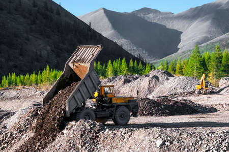 A dump truck unloads stones in a mining industrial areaの写真素材