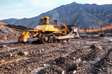 Bulldozer harrows the mountain soil, and then removes the top layer with an industrial bucket....