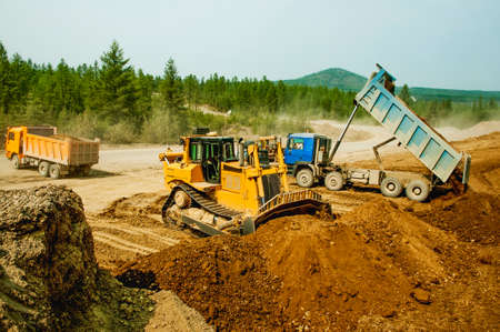 Excavation work, the bulldozer bucket moves the mountain soil to the sideの写真素材