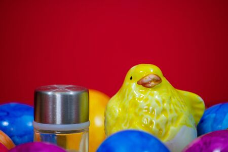 small salt shaker next to a clay chick and colorful Easter eggsの写真素材