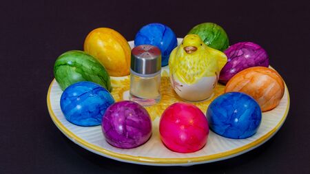 small salt shaker next to a clay chick and colorful Easter eggs