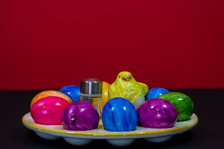 small salt shaker next to a clay chick and colorful Easter eggsの写真素材