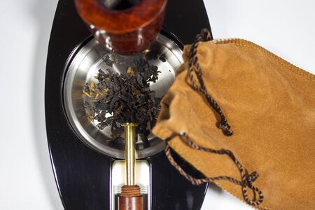 fresh tobacco in ashtray with pipe stopper and pipe