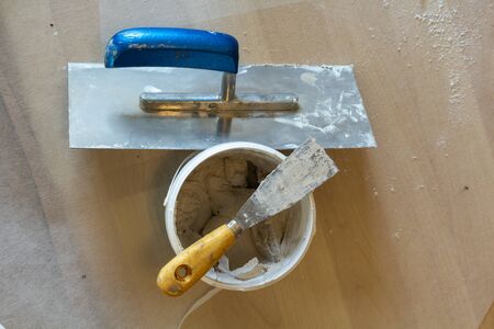 a small spatula on the bucket, with fresh putty, next to it a smoothing discの写真素材
