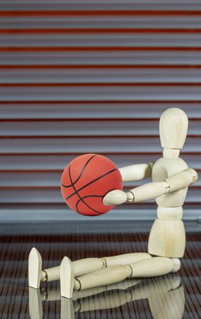 Wooden dummy with basketball in front of a jalousie plays with the ballの写真素材