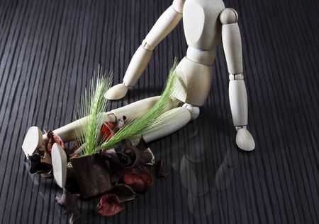 Wooden doll with fresh cereal stalks on the legs, many dried spring fruits lie next to itの写真素材
