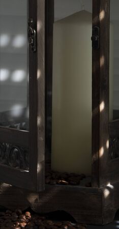 open wooden lantern shining on the sun's rays, with candle and coffee beans as decorationの写真素材