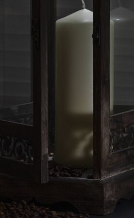 open wooden lantern shining on the sun's rays, with candle and coffee beans as decorationの写真素材