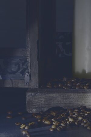 mystic scene of a wooden lantern in the light of a flashlight, coffee beans in front of it and a candle in the lanternの写真素材