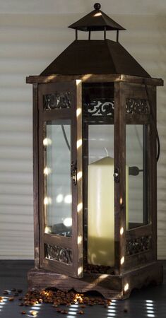 open wooden lantern shining on the sun's rays, with candle and coffee beans as decorationの写真素材