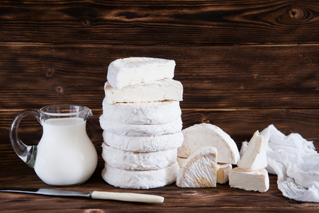 Whole camembert cheese and milk jug on rustic brown wooden backgroundの写真素材