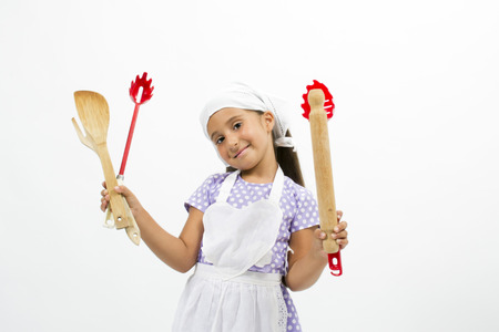 Adorable little girl chef with kitchen utensils and capの写真素材