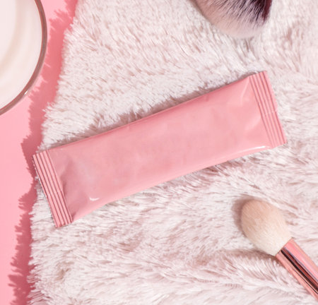 A pink makeup bag with a brush on it next to a plate of makeup.の写真素材