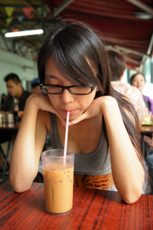 girl drinking a Hong Kong-style milk tea in Dai pai dongの写真素材