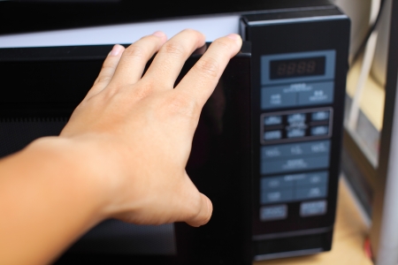 Hand using microwave ovenの写真素材