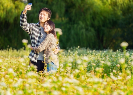 Asian couple take photo by mobile phone の写真素材