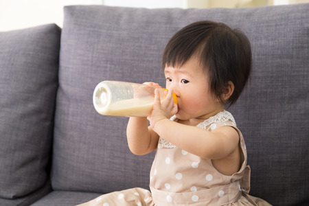 Adorable baby girl drinking milk from bottle の写真素材