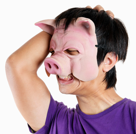 Man wearing pig mask with headacheの写真素材