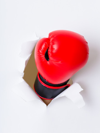 Boxing glove through a hole in paperの写真素材