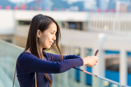 Happy woman using a smart phone in the streetの写真素材