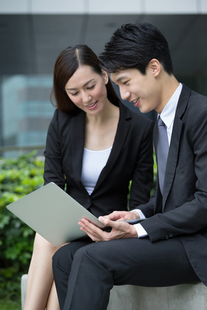 Businesswoman and man look at the laptop computer at outdoorの写真素材