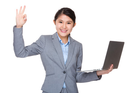 Asian businesswoman use of laptop and ok sign gestureの写真素材
