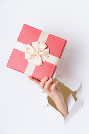 Hand break through paper with red gift boxの写真素材